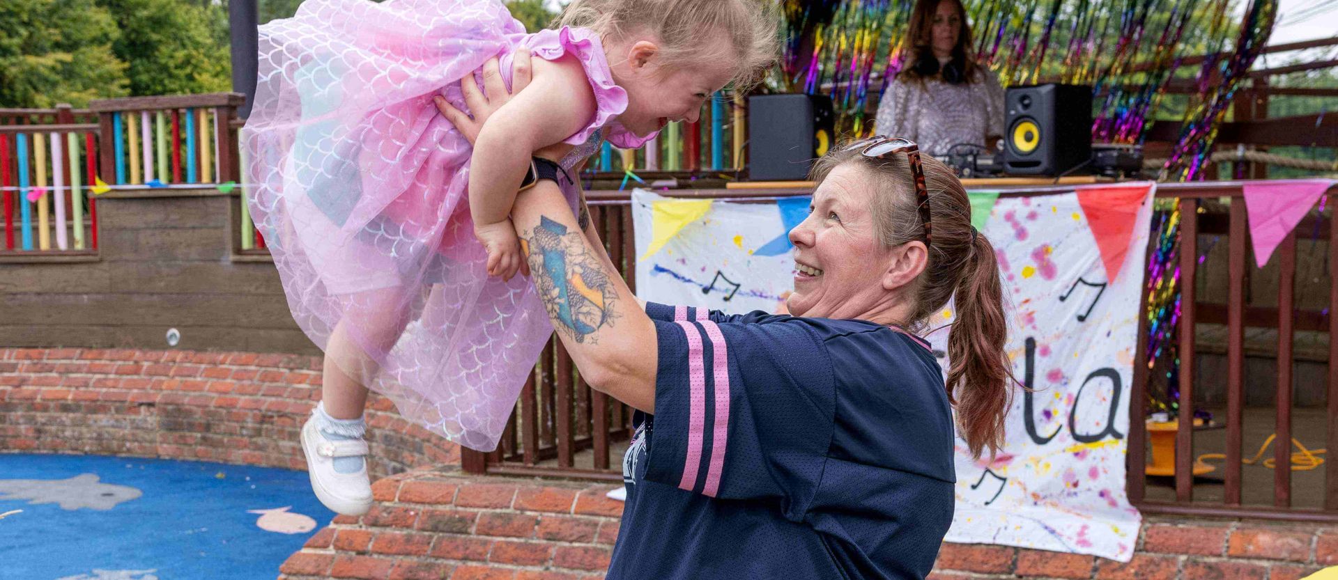 Mum throwing daughter up in air in garden, both laughing