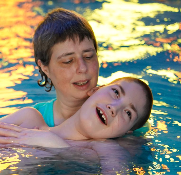 Boy and his mum in the pool swimming together