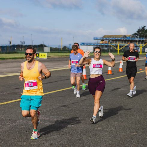 A group of people running and smiling on a runway