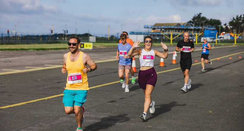 A group of people running and smiling on a runway