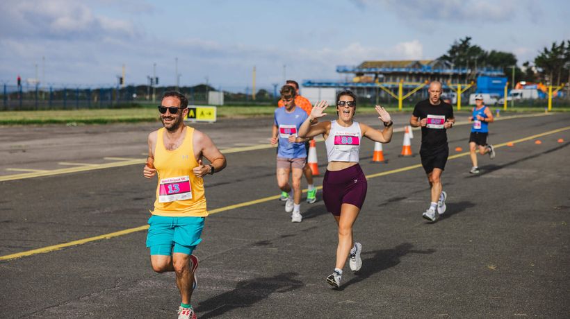 A group of people running and smiling on a runway