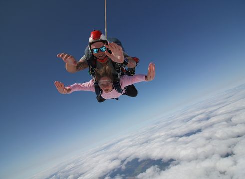 A women and man in the air doing a tandem skydive smiling