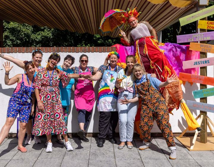 Staff dressed in colourful outfits outside with stilt walker