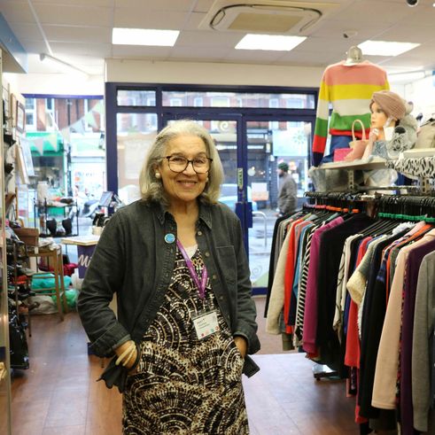 a volunteer woman smiling in a naomi and jacks charity shop