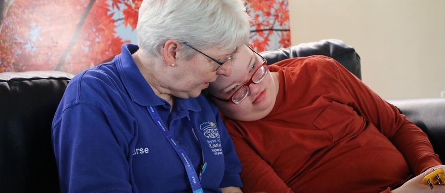 A nurse and a child embracing on a sofa