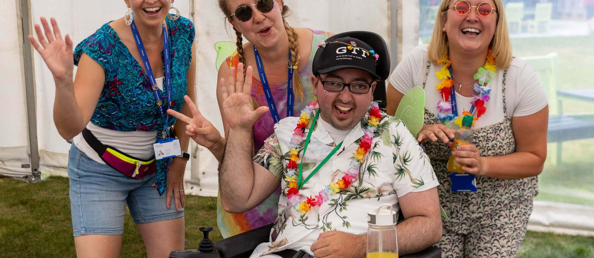 Young adult wearing lei surrounded by colourfully dressed staff