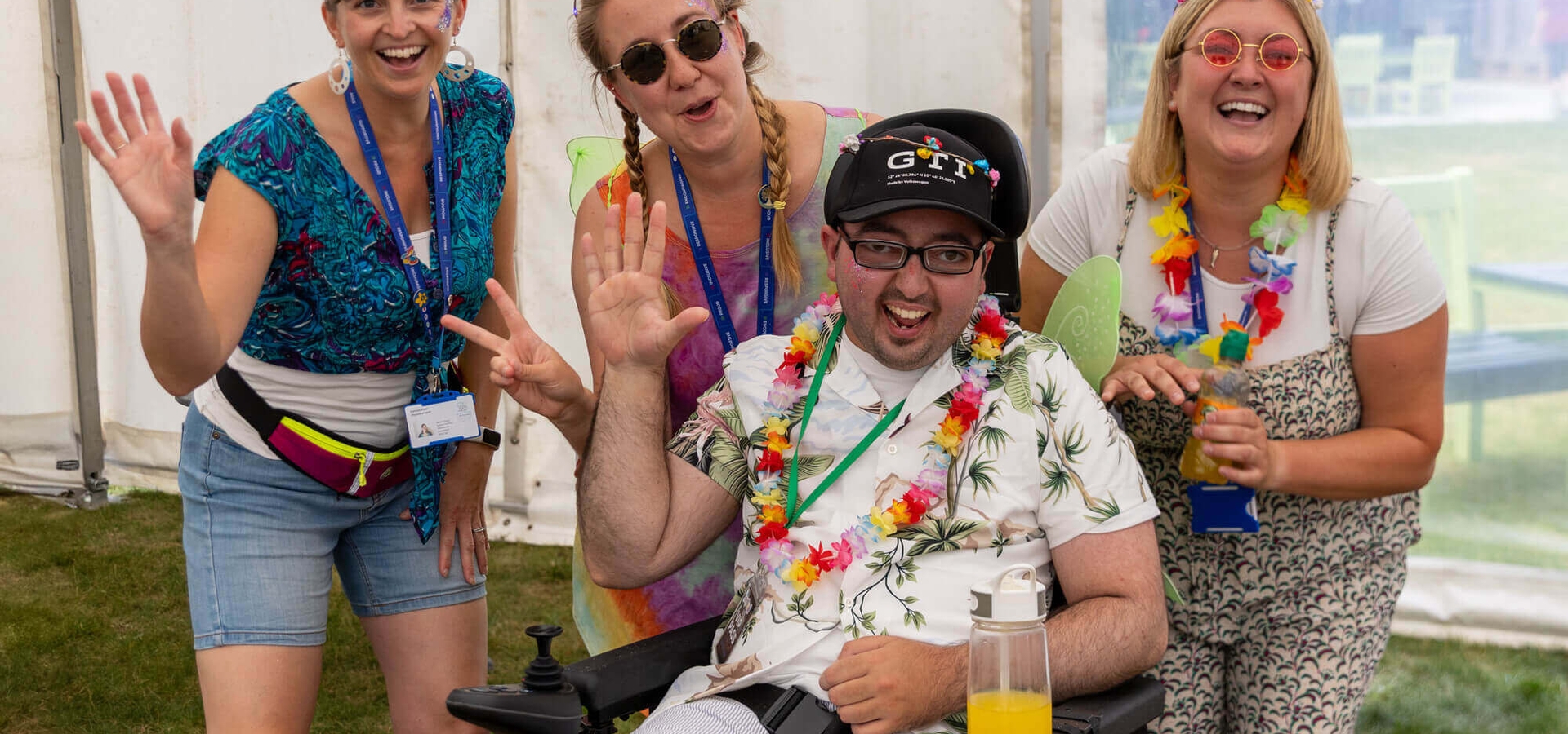 Young adult wearing lei surrounded by colourfully dressed staff