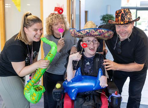 Nurse, young adult and their family posing for photo with silly props and hats