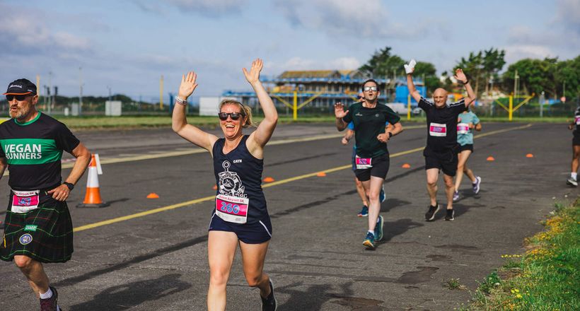 A lady running with her hands up smiling