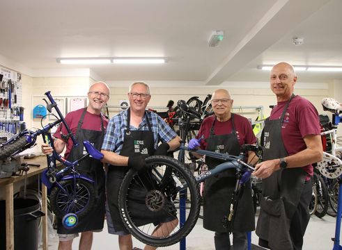 recycle bike hub volunteers smiling in the workshop by bicycles